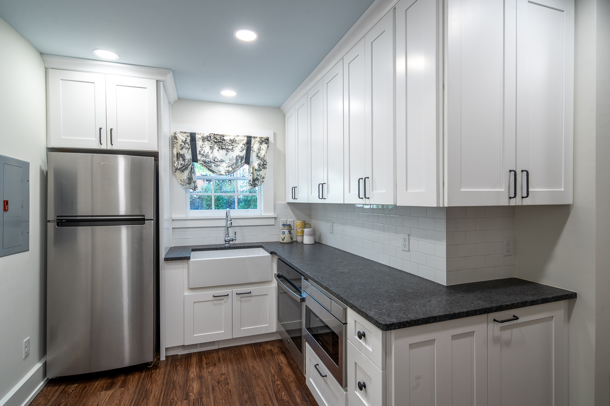 Updated kitchen with white cabinets, stainless steel appliances, and dark countertops.